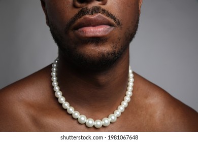 Close-up Of Shirtless Black Man With Pearl Necklace Over Grey Background.