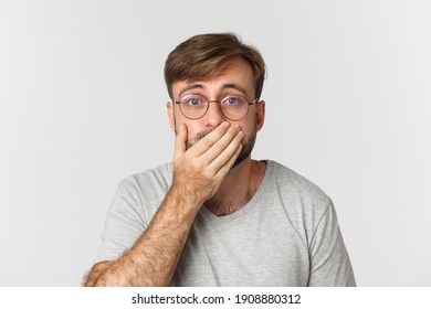 Close-up Of Shocked And Worried Man In Glasses, Gasping And Cover Mouth, Hear Something Scary, Standing Over White Background