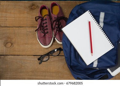 Close-up of shoes, spectacles, book, pencil, digital tablet and schoolbag on wooden table - Powered by Shutterstock