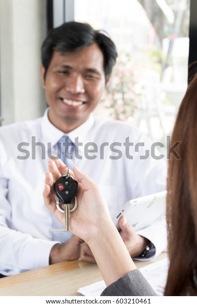 Close-up shoot of the car salesman hand giving a\
key to the owner.
