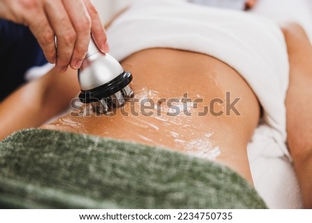 Close-up shoot of a unrecognizable woman getting a RF lifting treatment on abdomen at the beauty salon.