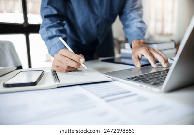 Close-up shot, asian businessman take a note and working with laptop at office. legal expert, professional lawyer checking business data and contract before giving advice to customers - Powered by Shutterstock