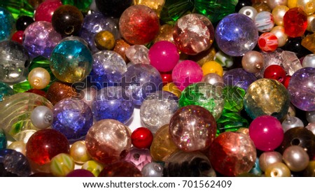 A closeup shot of assorted beads. Mixed altogether, the beads differ in sizes, colors, and shapes.  