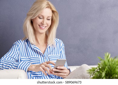 Close-up shot of an attractive blond woman using her cellphone and reading text messaging. 