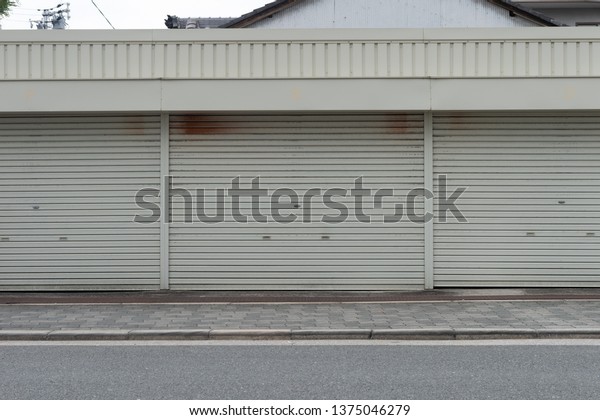 A closeup shot of automatic metal roller door\
used in factory, storage, garage, and industrial warehouse. The\
corrugated and foldable metal sheet offer space saving and provide\
urban and rustic feel