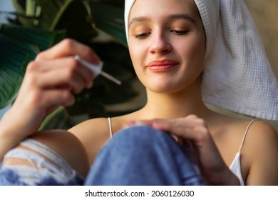 Close-up Shot Of A Beautiful Young Woman Getting Ready For Work. She Is Painting Her Nails While Covering Her Hair With A Towel After Washing.