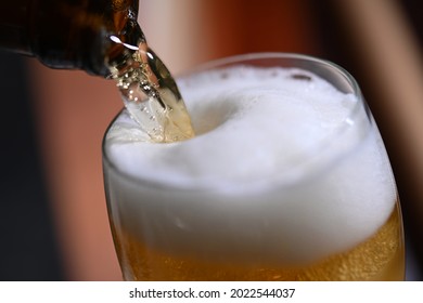 closeup shot of beer pouring from bottle into glass