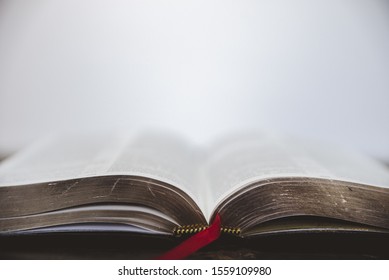 A Closeup Shot Of The Bible With Golden Pages And A Blurred Background