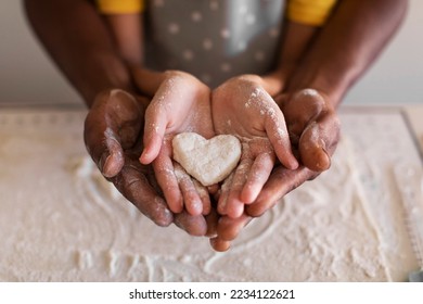 Closeup Shot Of Black Father And Little Daughter Holding Heart Shape Made Of Dough In Hands, Loving African American Family Dad And Female Child Baking Together In Kitchen, Cropped Shot - Powered by Shutterstock