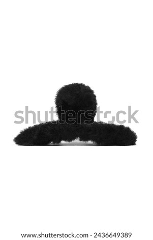 Close-up shot of a black fluffy hair clip. Plush hair claw clip is isolated on a white background. Front view. A fashionable hair accessory with fur.