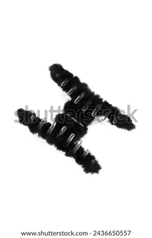 Close-up shot of a black fluffy hair clip. Open plush hair claw clip is isolated on a white background. Front view. A fashionable hair accessory with fur.