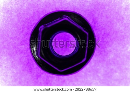 A close-up shot of a black hexagonal nut against a vibrant purple background.
