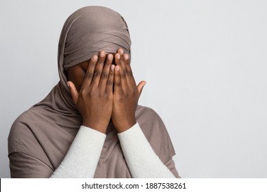 Closeup Shot Of Black Muslim Woman In Hijab Covering Face With Hands, Crying African Islamic Lady Suffering Religious Discrimination, Rasicm Or Islamophobia, Standing Over Light Background, Copy Space