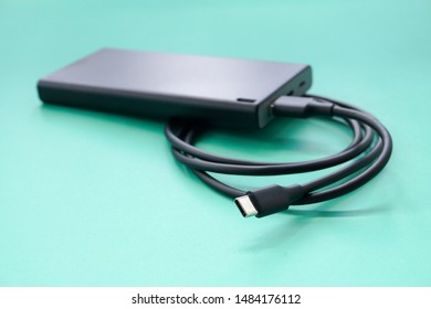 Closeup Shot Of A Black Power Bank With USB Type C Cable On Turquoise Background