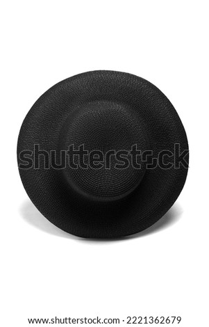Close-up shot of a black straw wide-brimmed hat. The black straw sun hat with a rounded downward brim is isolated on a white background. Front view.