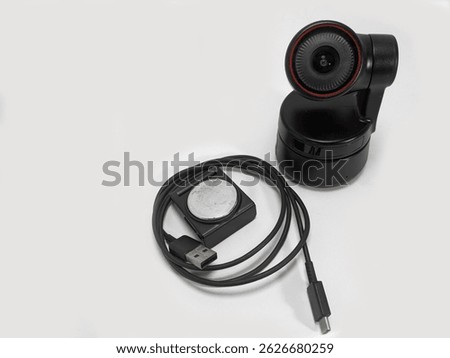 Close-up shot of a black webcam and its USB cable lying on a white surface highlighting its sleek design and technology features