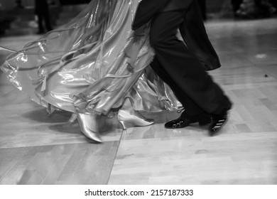 A closeup shot in black and white of the dance couple's legs while dancing a waltz