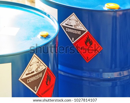 the close-up shot of blue color hazardous dangerous chemical barrels ,have warning labels of corrosive & flammable liquid in daylight on daytime.