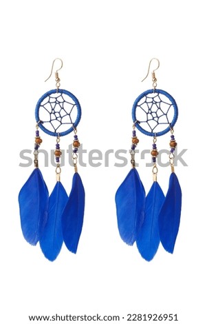 Close-up shot of blue dreamcatcher earrings decorated with feathers and beads. A pair of ethnic style hook earrings is isolated on a white background. Front view.