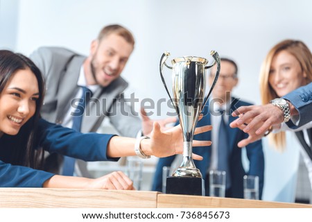close-up shot of businesspeople trying to catch champion cup