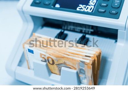 A closeup shot captures a machine accurately counting a substantial stack of fifty Euro banknotes