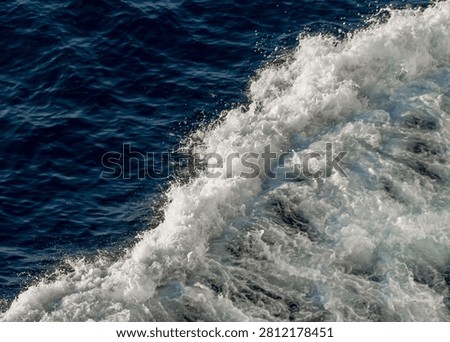 Close-up shot capturing the immense power of ocean waves crashing, creating beautiful, frothy sea foam and intricate water texture details.