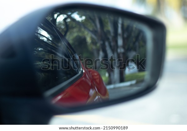 A closeup shot of a car\'s mirror reflecting what\
is behind