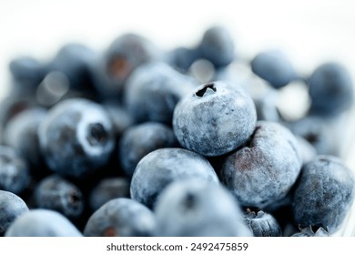 A close-up shot of a ceramic bowl filled with fresh blueberries. The glossy blue fruits are piled high, showcasing their vibrant color and juicy texture. - Powered by Shutterstock