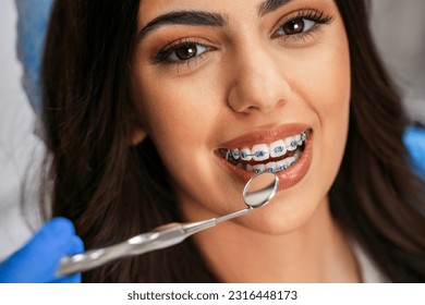 Closeup shot of charming young woman with dental braces having checkup , looking at camera, beautiful eye glow 