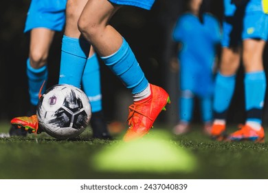 closeup shot of children in blue uniforms and socks kicking a ball on a field, kids soccer concept. High quality photo - Powered by Shutterstock