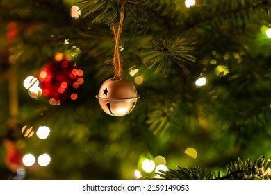 A close-up shot of a Christmas ball hanging on a lit Christmas tree