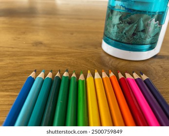 A close-up shot of colorful pencils and sharpener neatly arranged on a wooden desk, for art, creativity, and school projects. - Powered by Shutterstock