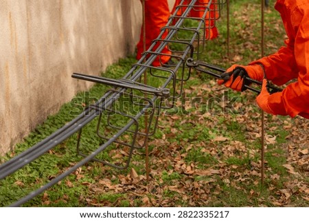 Close-up shot of construction worker using pincer pliers to tie rebar stirrups for concrete beam
