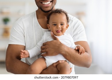 Closeup Shot Of Cute Funny Black Baby Boy Relaxing In Father's Arms, Happy African American Dad Holding His Adorable Infant Child, Enjoying Bonding With Little Kid At Home, Cropped, Free Space