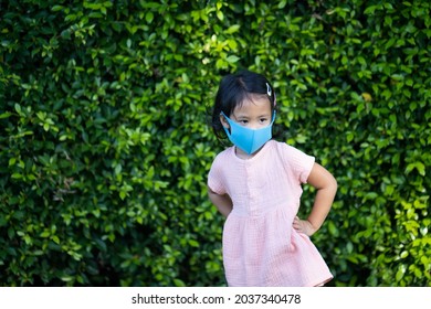 A Closeup Shot Of A Cute South Asian Child With A Mask In A Green Garden