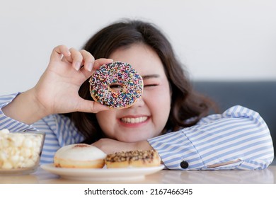 Closeup Shot Of Delicious Chocolate Donut Decorated With Colorful Sugar Sprinkles In Asian Young Happy Beautiful Long Black Hair Oversized Fat Female Model Hand Who Smile Look Through Doughnut Hole.