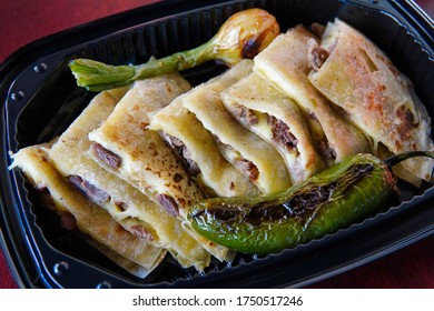 A Closeup Shot Of Delicious Mexican Quesadillas With Roasted Green Chili Peppers And Onion In A Plastic Container