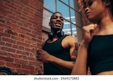 Close-up shot of a determined African-American woman jogger running past an African-American man on a city street - Powered by Shutterstock