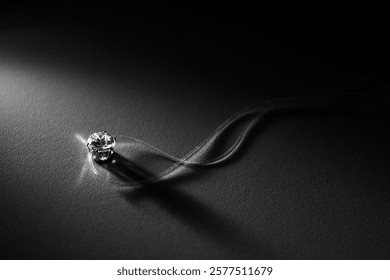 A close-up shot of a diamond pendant on a delicate string, illuminated on a dark background. Ideal for showcasing luxury, elegance, jewelry advertising, and minimalist design concepts.