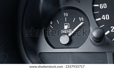 Close-up shot of a diesel fuel gauge in a car. The meter pointer showing that the tank is completely full. Glare of light present on the gauge glass cover. Copy space