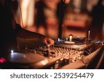 A close-up shot of a DJ using a mixing console and turntables at an event, showcasing the atmosphere of a lively party or music festival