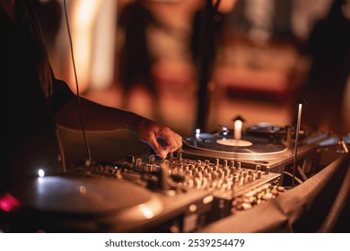 A close-up shot of a DJ using a mixing console and turntables at an event, showcasing the atmosphere of a lively party or music festival