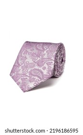 Close-up shot of an elegant purple and white tie embossed with a floral paisley pattern. The paisley purple and white tie is rolled and isolated on a white background. Top view.