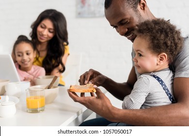 Close-up Shot Of Father Applying Peanut Butter On Toast For Son At Kitchen