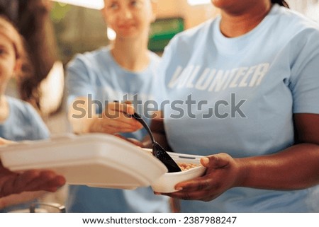 Close-up shot of female charitable group providing free food to underprivileged and homeless people. Volunteer holding meal box for distributing to the hungry and needy individuals at local shelter.