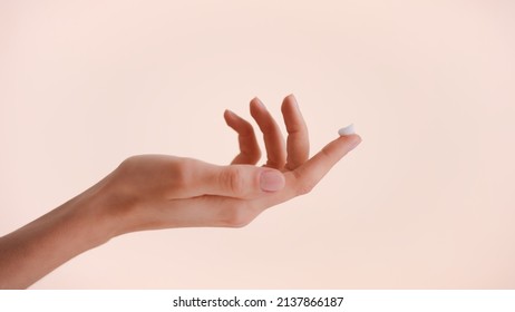 Close-up Shot Of A Female Hand With A Drop Of Beauty Cream On The Top Of The Finger Against Beige Background