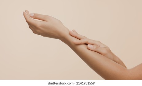 Close-up shot of female hands strokes each other on beige background | Hand and body care commercial concept - Shutterstock ID 2141931559
