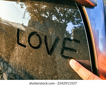 A close-up shot of a finger tracing the word "love" in dust on a car window, symbolizing affection. - Powered by Shutterstock