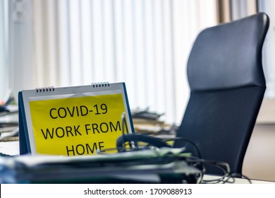 Closeup Shot Focusing On A Sign 'Work From Home' Worker Puts On A Desk. Office Is Empty. Employee Of A Business Company Works Remotely And Applies Social Distancing To Prevent COVID-19 Infection.