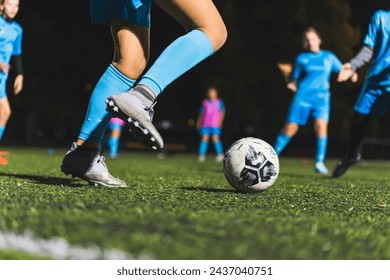 closeup shot of girls with blue uniforms practicing football on a green field at night, girls sport. High quality photo - Powered by Shutterstock